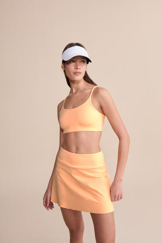 A woman wearing a red sports bra made with a bandeau-style design and thin straps.