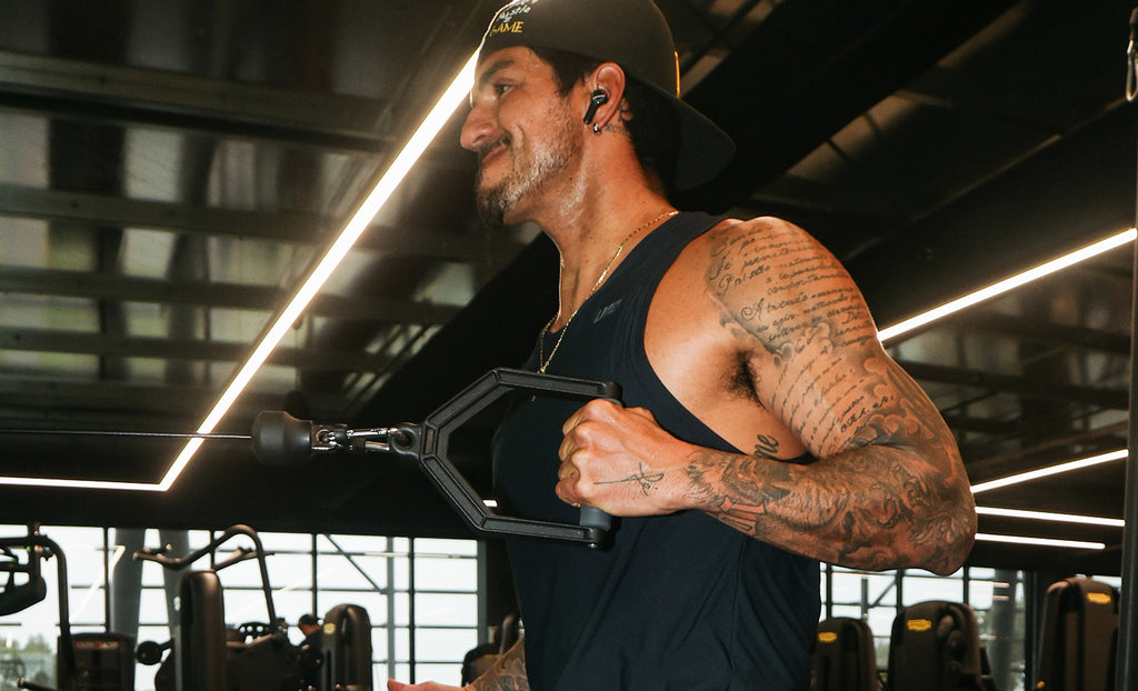 Man performing a cable row exercise while wearing black activewear in a gym.