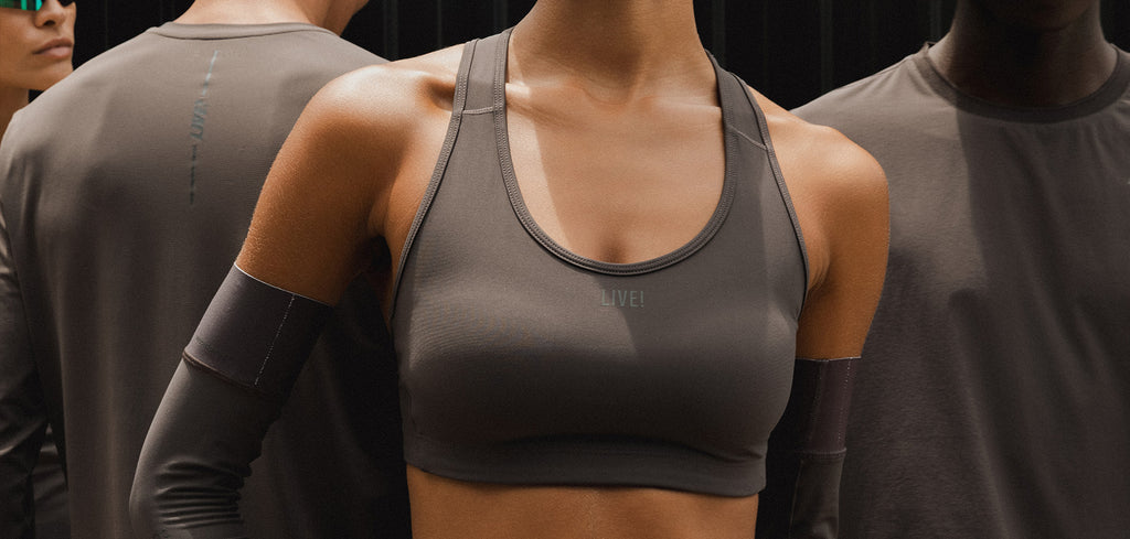 Person wearing a gray sports bra and long-sleeve top against a dark background