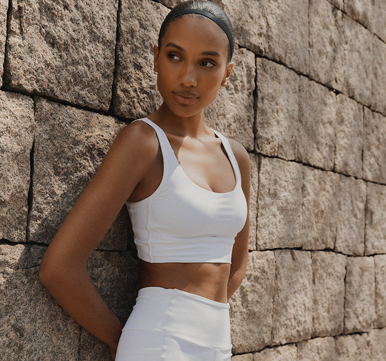 Woman wearing a LIVE! Activewear set in front of a stone block wall